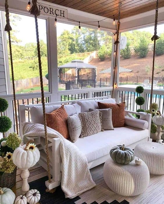 swings, pumpkins, and flowers for fall porch